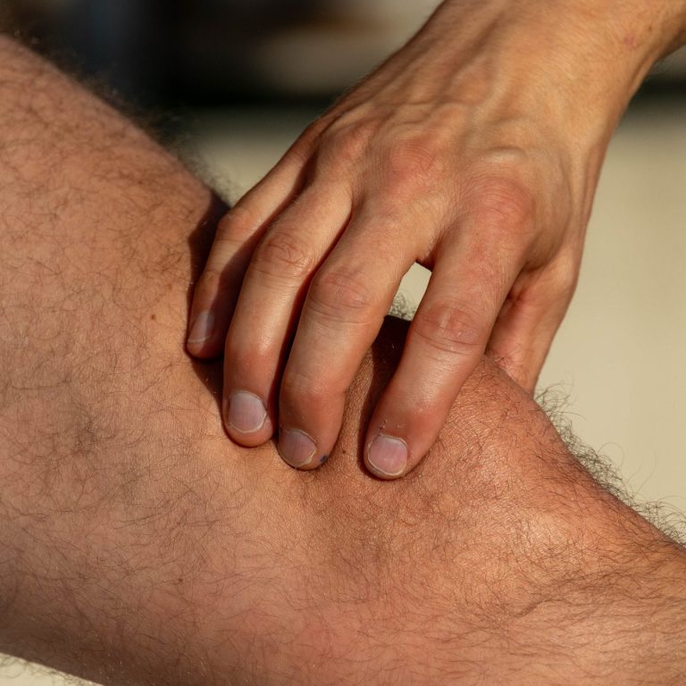 Dr. Güth untersucht mit seiner Hand das Kniegelenk eines Patienten.